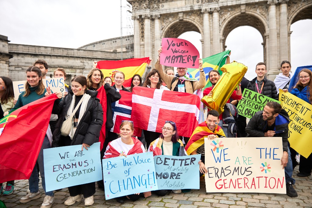 Young people at an Erasmus+ youth exchange holding flags and signs